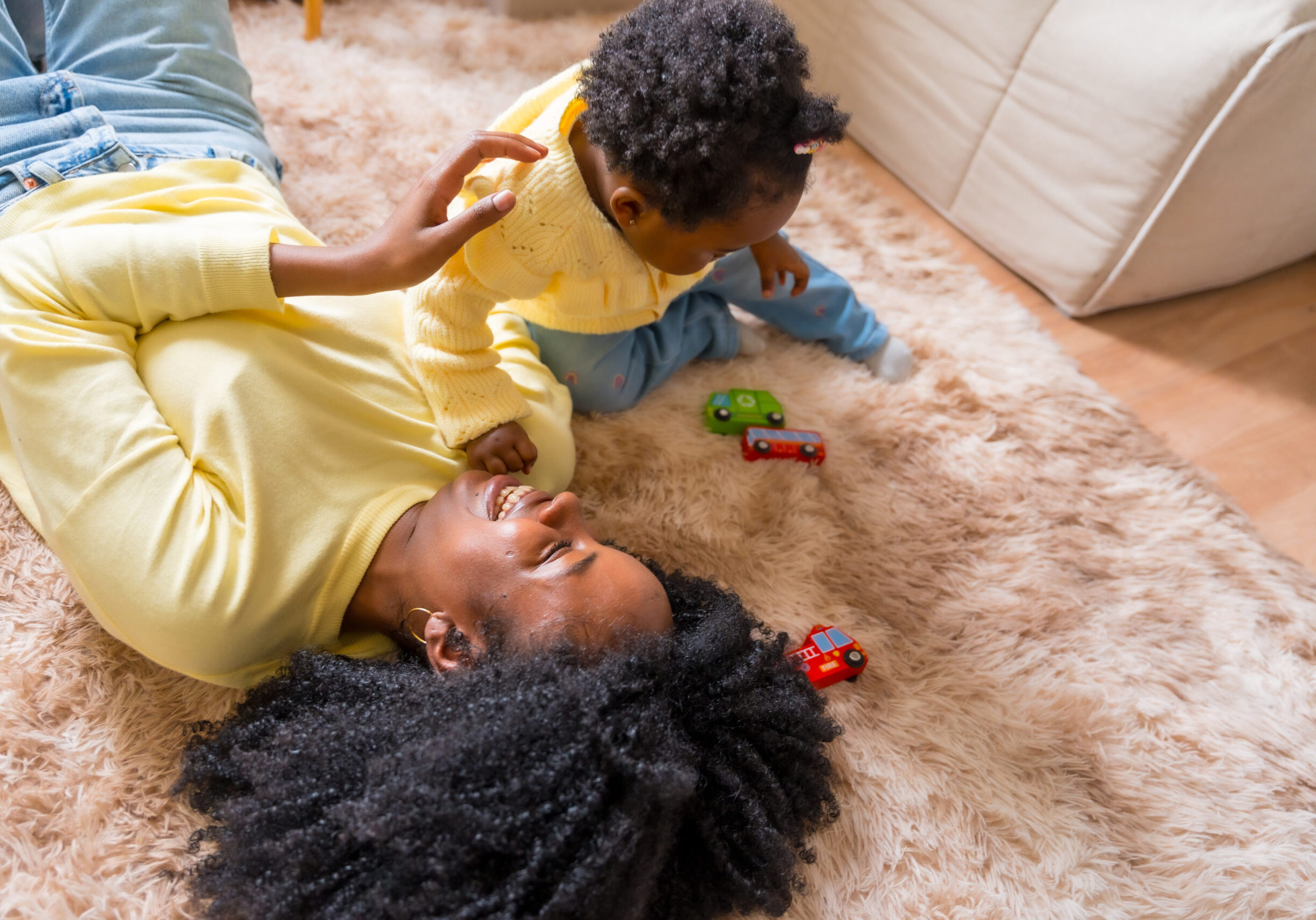 Top view of an african mother lying on the floor while the daughter playing at home